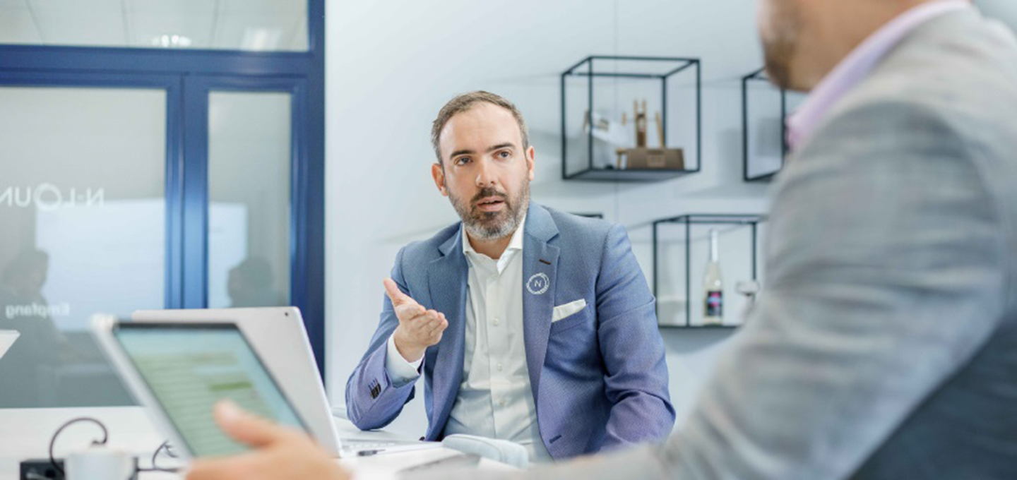 A person in a suit talking to another person